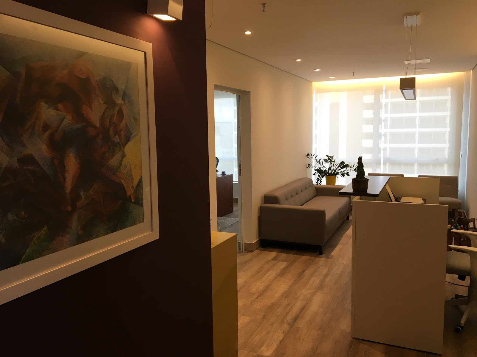 Recepção do consultório do Dr. Ivo, com balcão, quadro na parede e plantas