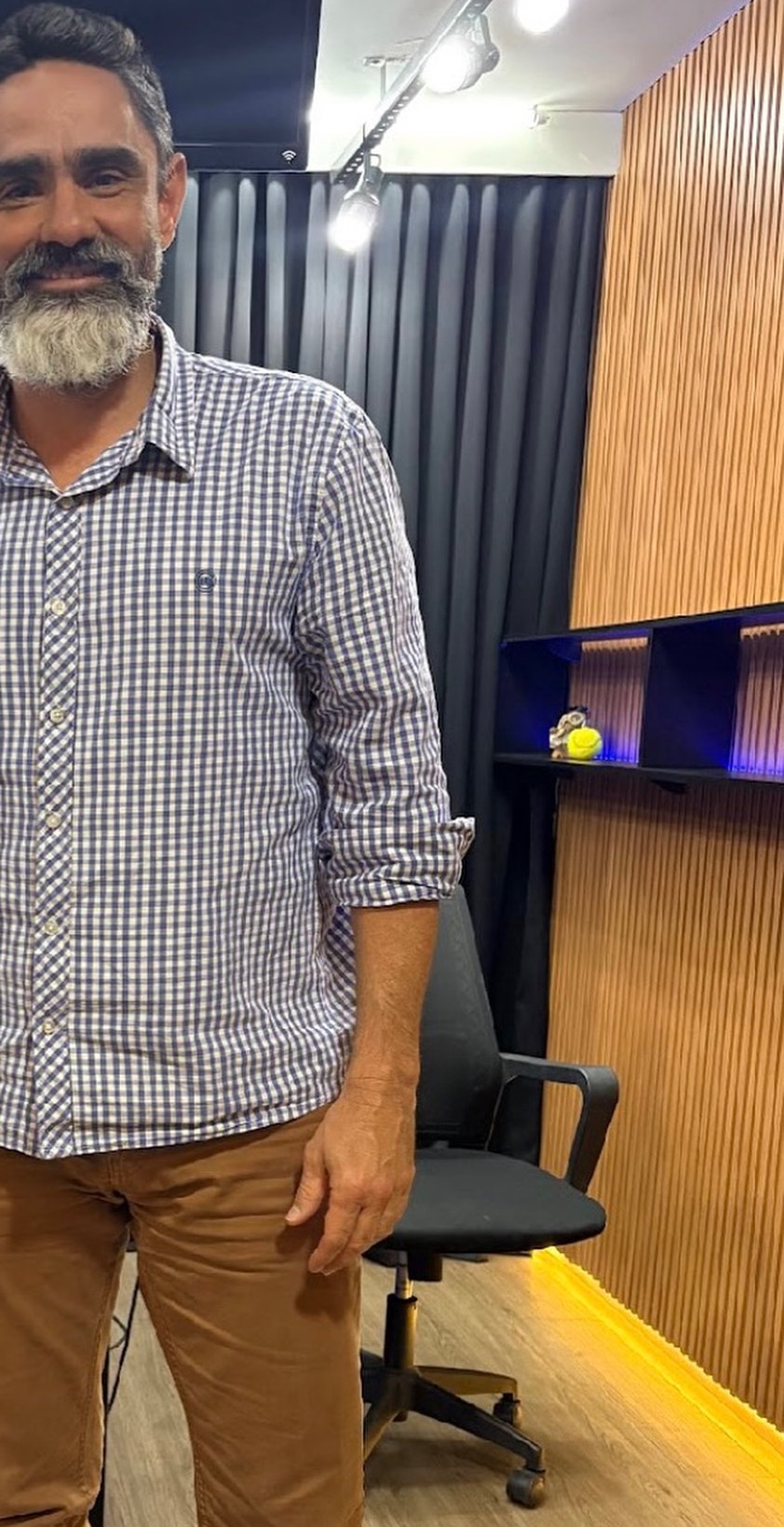 Dr. Ivo Pinfildi Neto, psiquiatra, sorrindo em pé no estúdio de gravação